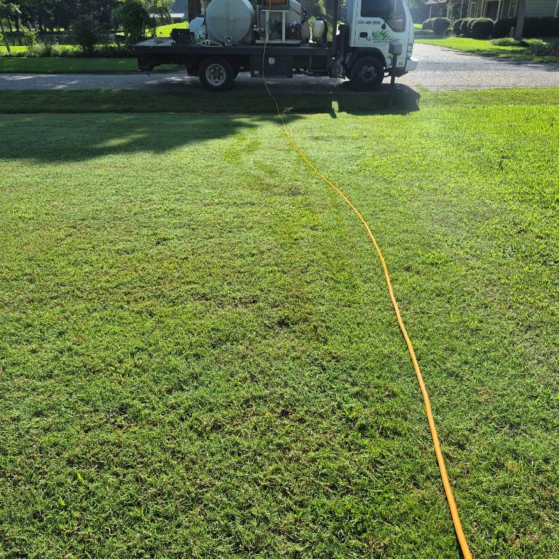 Grow Green service truck beside a lawn with a yellow treatment hose across the grass